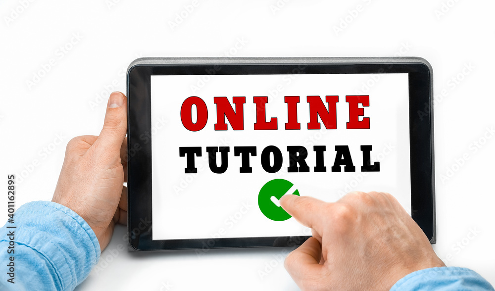Closeup of a male hands holding tablet pc with text Online Tutorial Closeup of a male hands holding tablet pc with text Online Tutorial