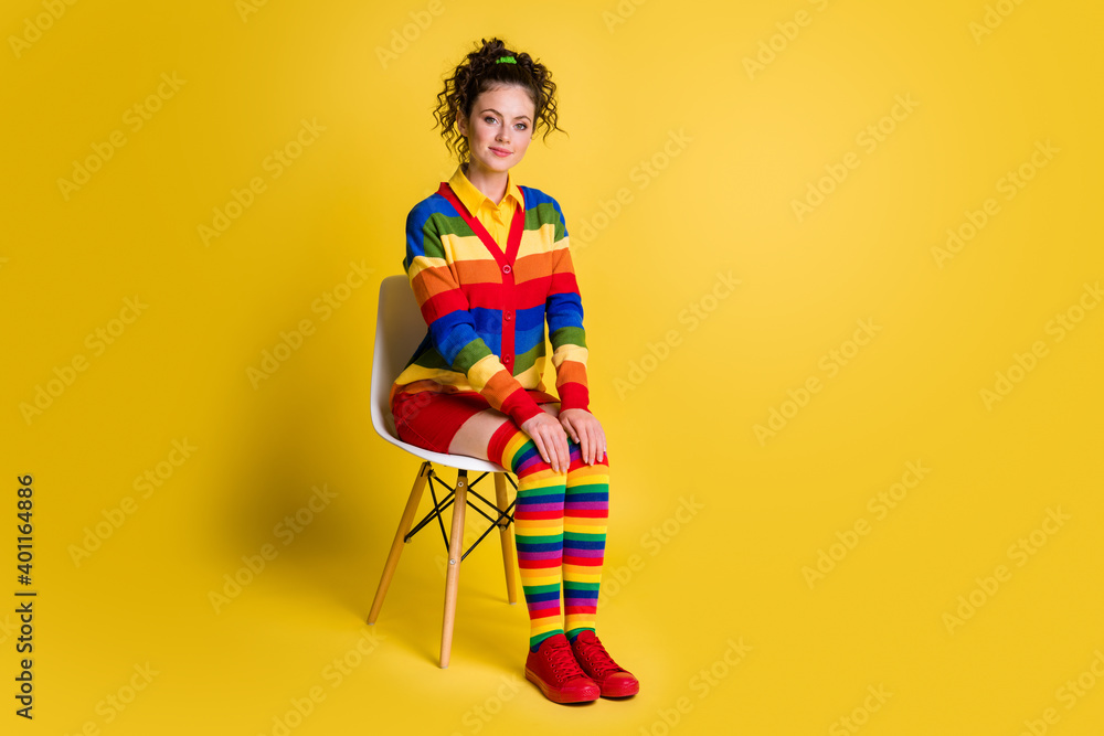 Full size photo of pretty girl sit chair wear colorful striped clothes isolated shine color background Full size photo of pretty girl sit chair wear colorful striped clothes isolated shine color background