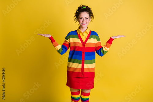 Photo of attractive lady hold two open arms advertisement concept wear striped sweater short skirt isolated yellow color background