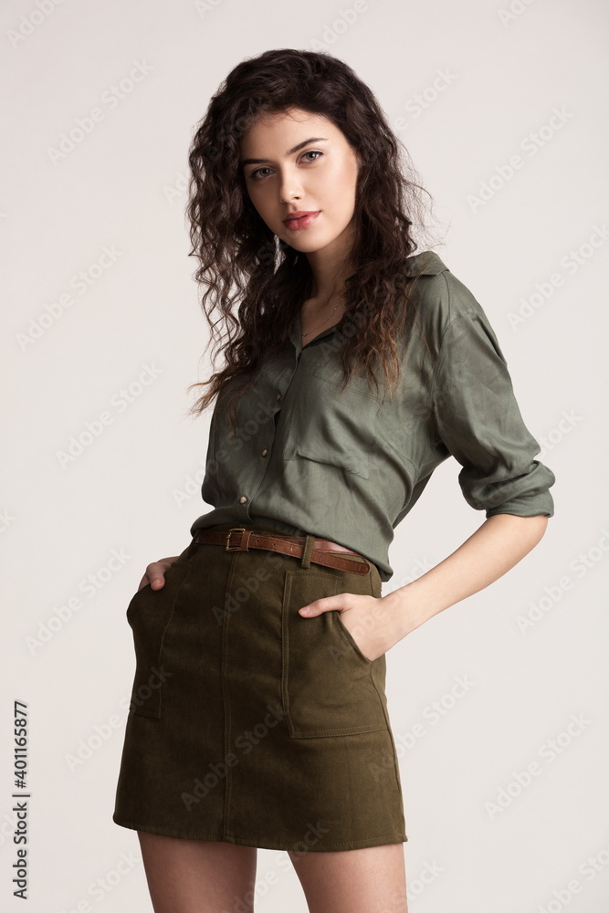 Beautiful sexy girl in a short green skirt and shirt posing in the studio on a white background Beautiful sexy girl in a short green skirt and shirt posing in the studio on a white background