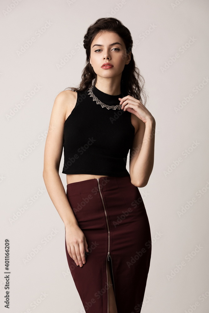 Beautiful sexy girl in a brown long skirt and black blouse posing in the studio on a white background Beautiful sexy girl in a brown long skirt and black blouse posing in the studio on a white background