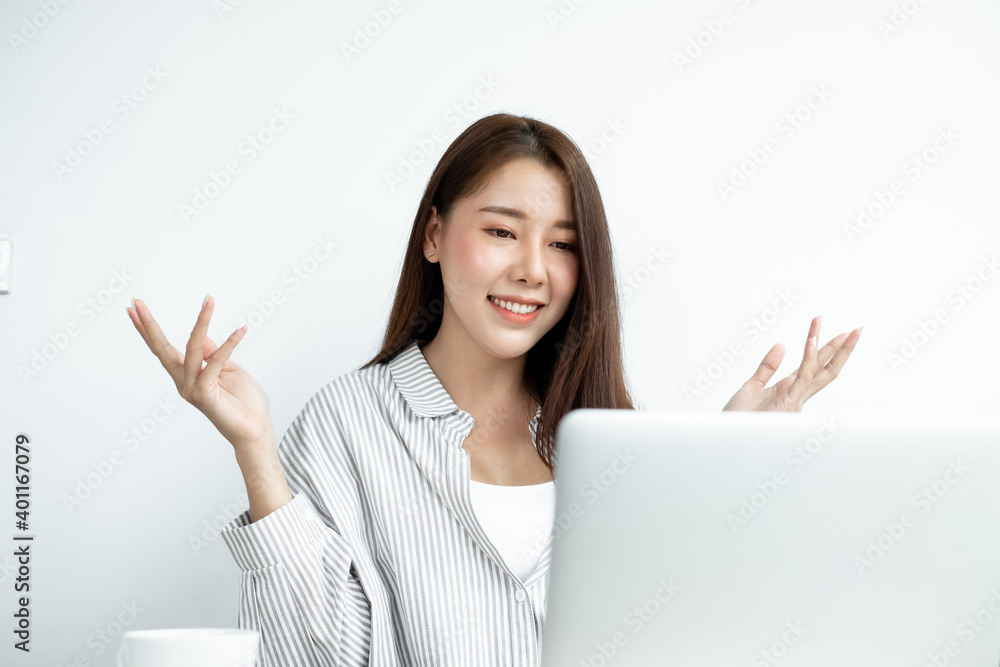 Video call, a young Asian woman communicates via online video long distance, looking at the digital laptop screen, happily greeted with a friend Video call, a young Asian woman communicates via online video long distance, looking at the digital laptop screen, happily greeted with a friend