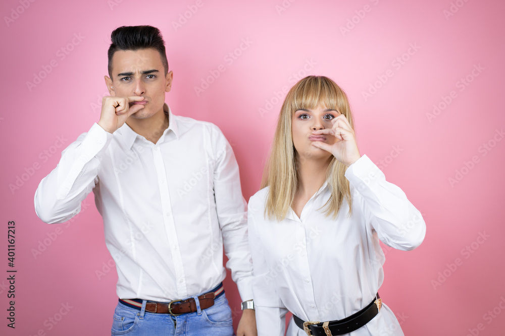 Obraz premium Young couple of girlfriend and boyfriend over isolated pink background mouth and lips shut as zip with fingers. Secret and silent, taboo talking
