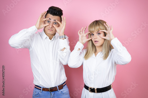 Young couple of girlfriend and boyfriend over isolated pink background Trying to open eyes with fingers, sleepy and tired for morning fatigue