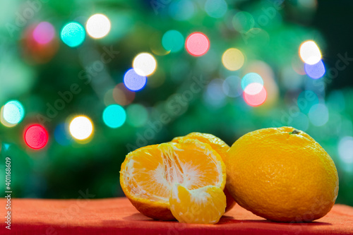 Fresh Clementines or Tangerines on table with red tablecloth with Xmas Lights.