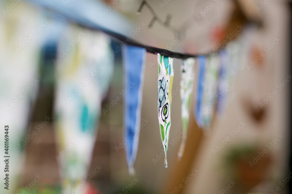 Fototapeta premium Bunting in the form of small traingular flags made of material hanging between trees in a suburban backyard