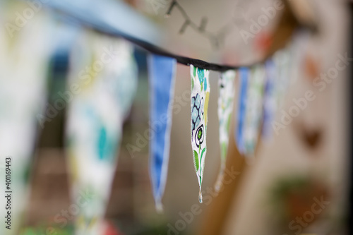 Bunting in the form of small traingular flags made of material hanging between trees in a suburban backyard