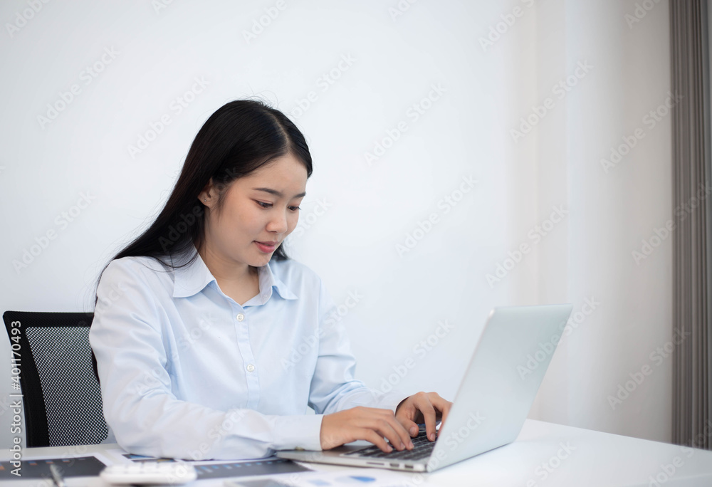 An Asian woman looks good and is pretty working on a laptop Business women are busy working with laptop computers in the office An Asian woman looks good and is pretty working on a laptop Business women are busy working with laptop computers in the office
