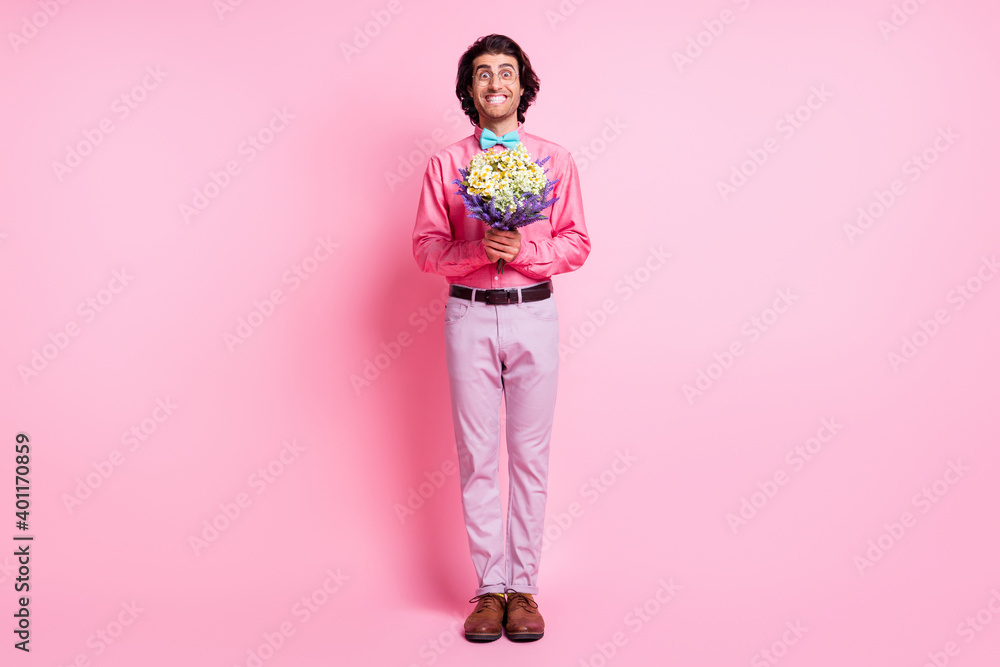 Full length photo of handsome brown haired young gentleman hold bouquet wear glasses isolated on pink color background Full length photo of handsome brown haired young gentleman hold bouquet wear glasses isolated on pink color background