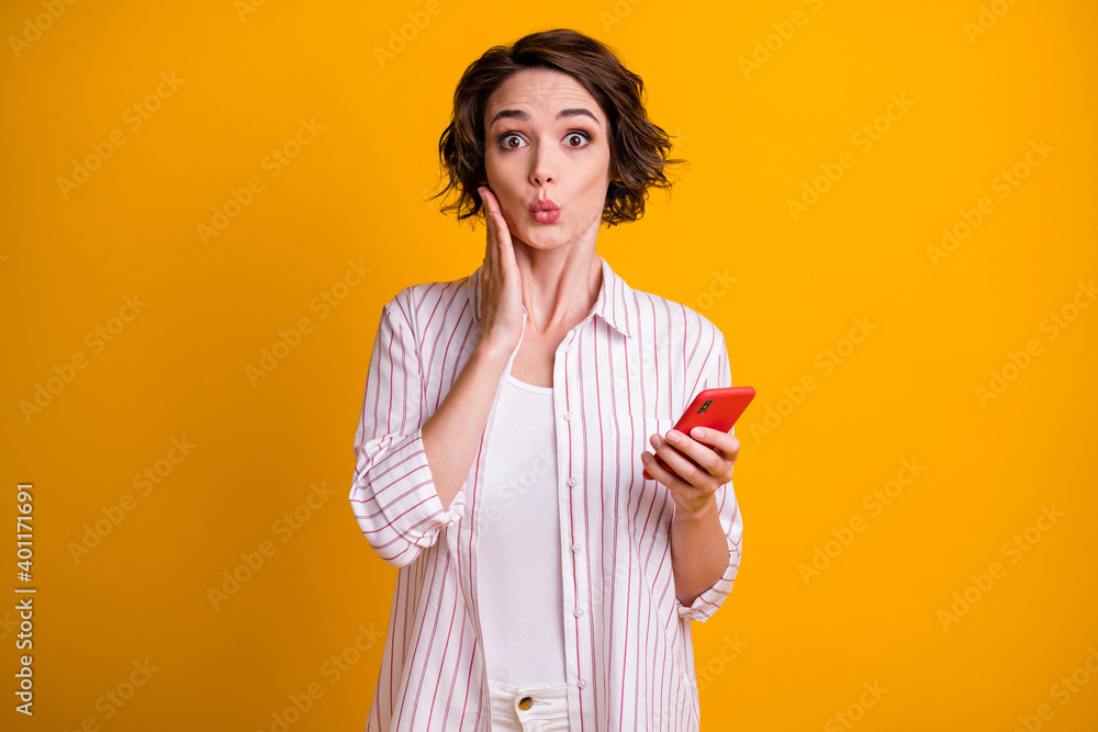 Photo of astonished girl use smartphone impressed social media information touch hand face wear good look clothes isolated over vivid color background Photo of astonished girl use smartphone impressed social media information touch hand face wear good look clothes isolated over vivid color background