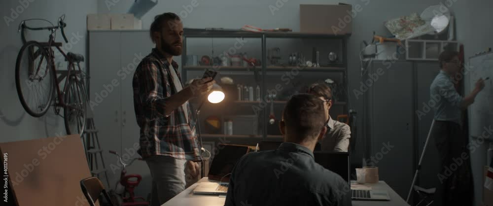 Young people celebrate after receiving good news call from client or investor, small business concept. Launching their small IT startup company from garage