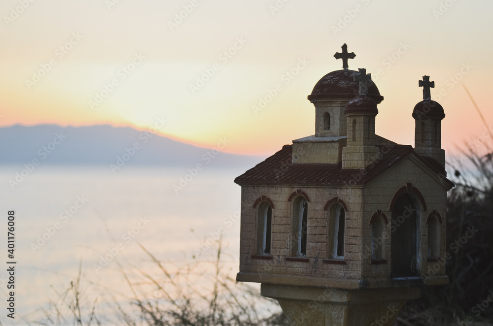 A Greek orthodox miniature church in the sunset at the sea