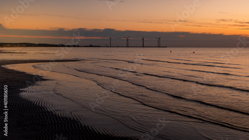 Beautiful sunset. golden, orange, blue colors over the sea. sky full of many colors. windmills in the background