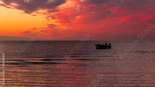 Beautiful sunset. pink, purple, golden, orange, blue colors over the sea. sky full of many colors. Boat in the water © Karlaage