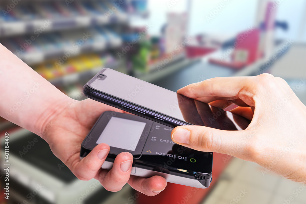 Pos terminals and smartphone. In the background is a supermarket checkout. Banking equipment. Acquiring. Acceptance of bank credit cards. Contactless payment... Pos terminals and smartphone. In the background is a supermarket checkout. Banking equipment. Acquiring. Acceptance of bank credit cards. Contactless payment...