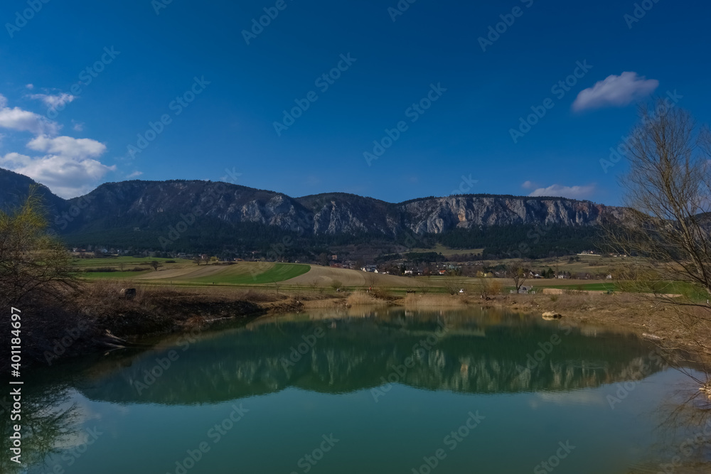 reflection from long rocky mountain range in a pond with blue sky