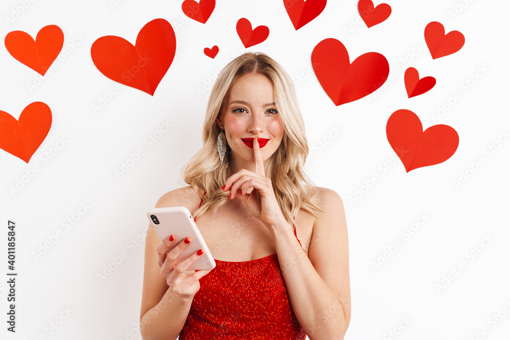 Beautiful young girl holding finger at her lips and holding cellphone Beautiful young girl holding finger at her lips and holding cellphone