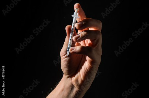 Hand with injection syringe on black background 