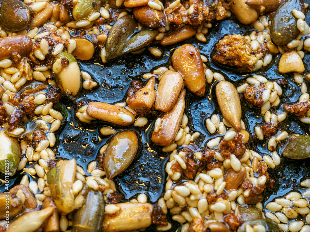 Assorted seeds being fried in oil in a frying pan Assorted seeds being fried in oil in a frying pan