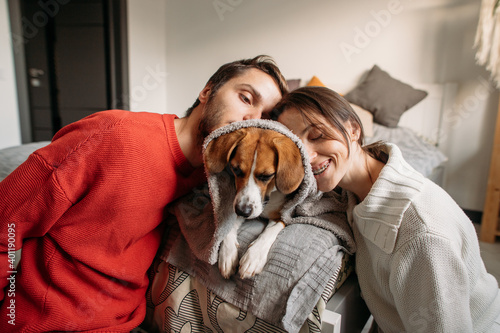 happy couple in love with a beagle dog sitting on the bed