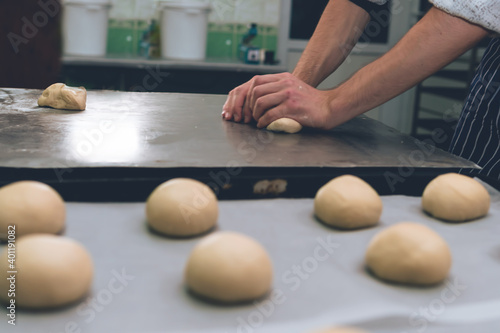The man is kneading the dough. Hamburger buns. Bakery, production. Copy space. Selective focus