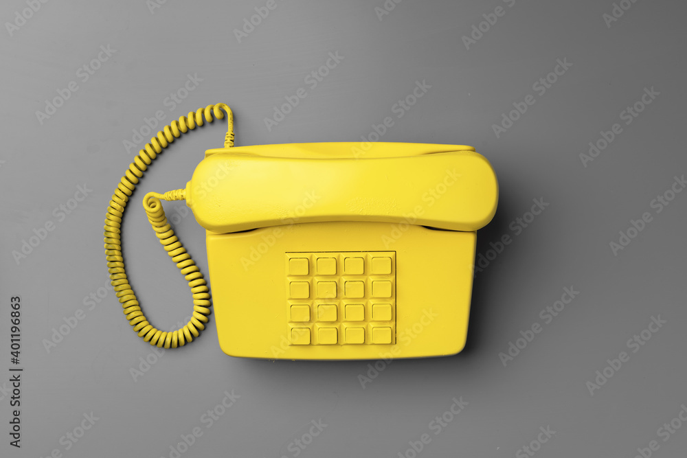 Yellow .landline phone on gray background top view Yellow .landline phone on gray background top view