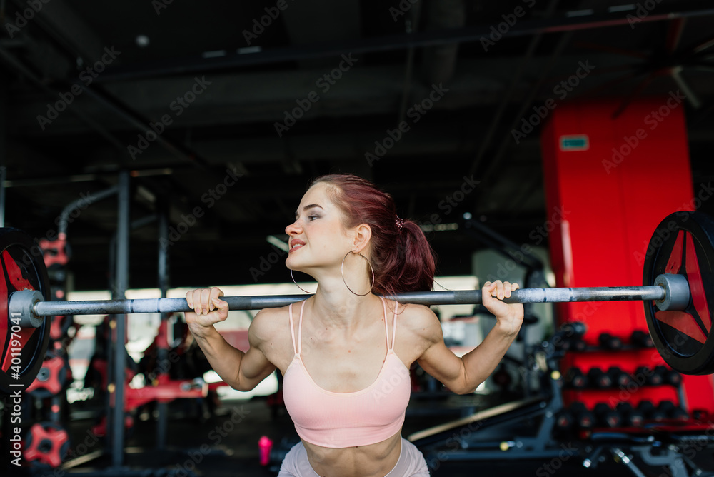 Athletic girl in sportswear performs exercises with barbell, dumbbells. Fitness, healthy lifestyle