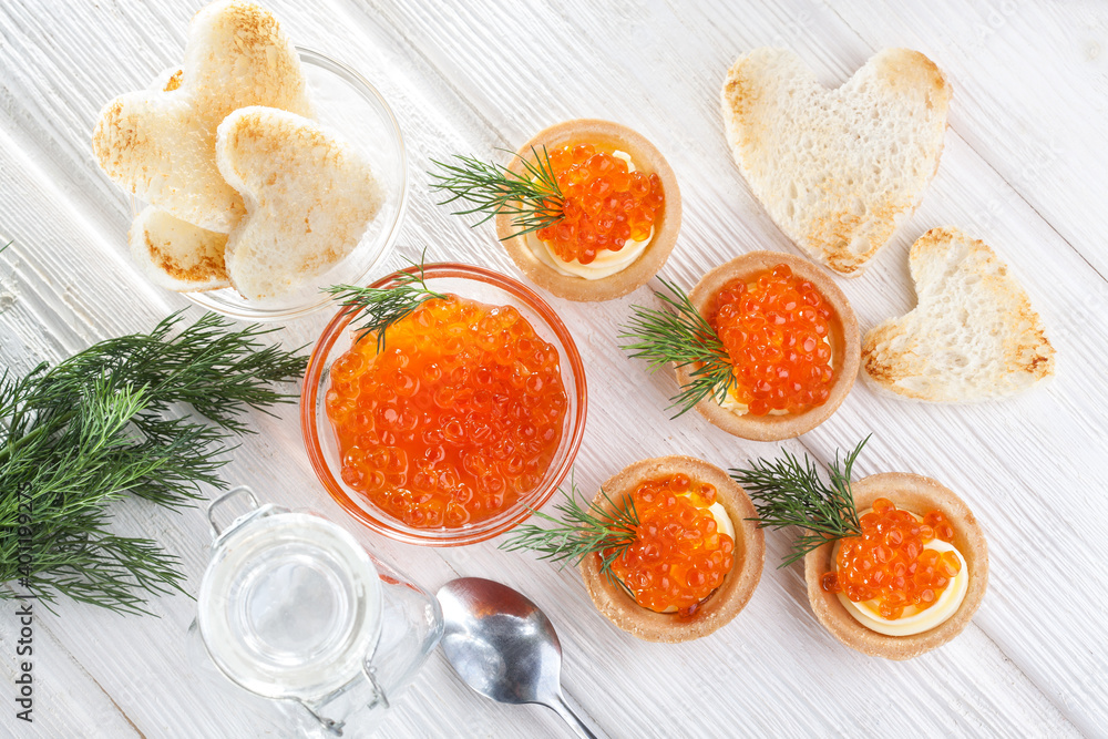 tartlets with butter and red caviar and dill on the white wooden table. Delicious snack Top view tartlets with butter and red caviar and dill on the white wooden table. Delicious snack Top view