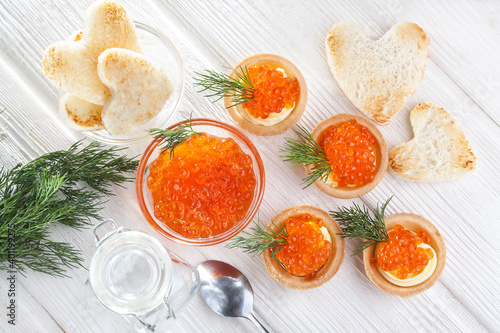 tartlets with butter and red caviar and dill on the white wooden table. Delicious snack Top view
