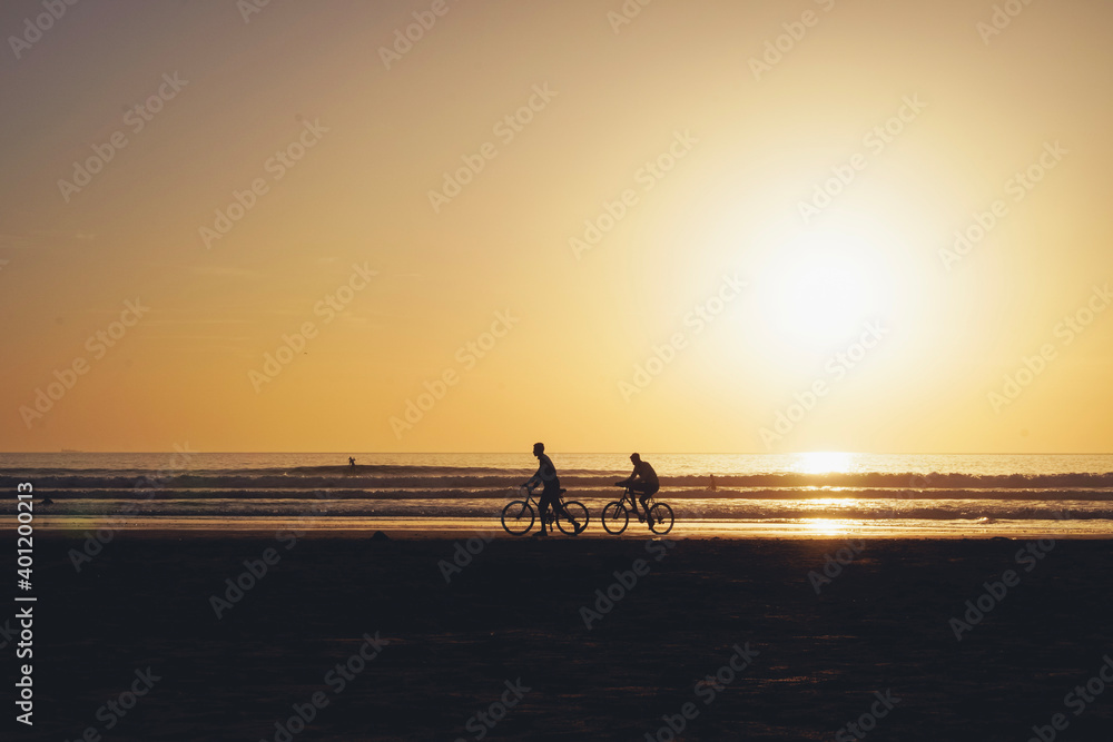 Surfers and people enjoying beach during sunset in Taghazout, Morocco