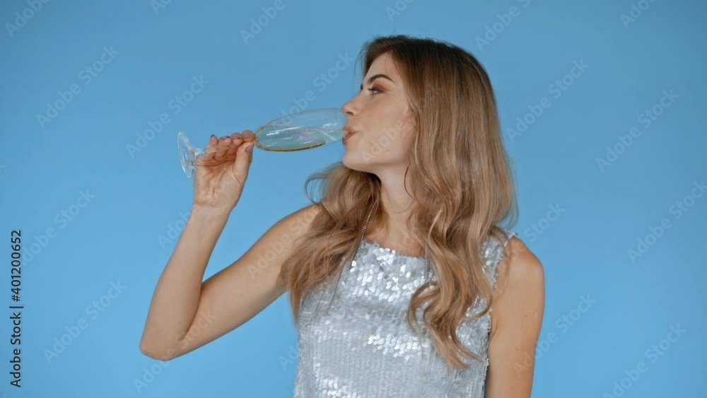 Smiling woman drinking champagne isolated on blue Smiling woman drinking champagne isolated on blue