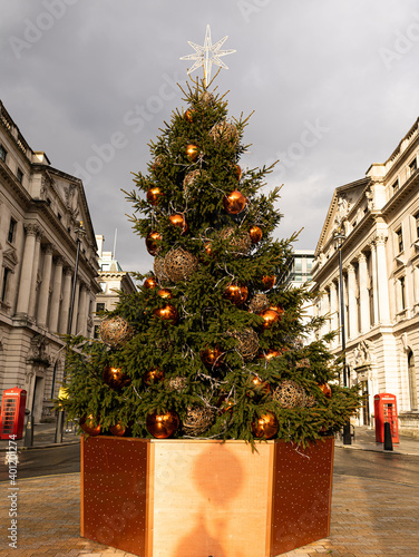 Close-up photo of a Christmas tree with two English telephone boxes located at Waterloo Place, London, United Kingdom