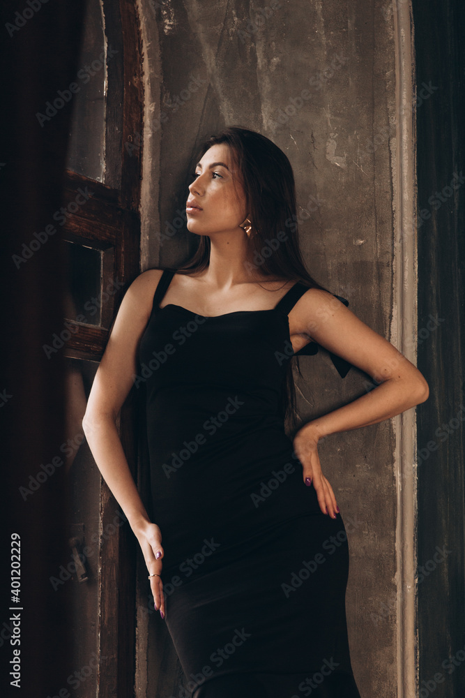 Fototapeta premium Fashion photoshooting in a photo studio of a beautiful girl in a black dress