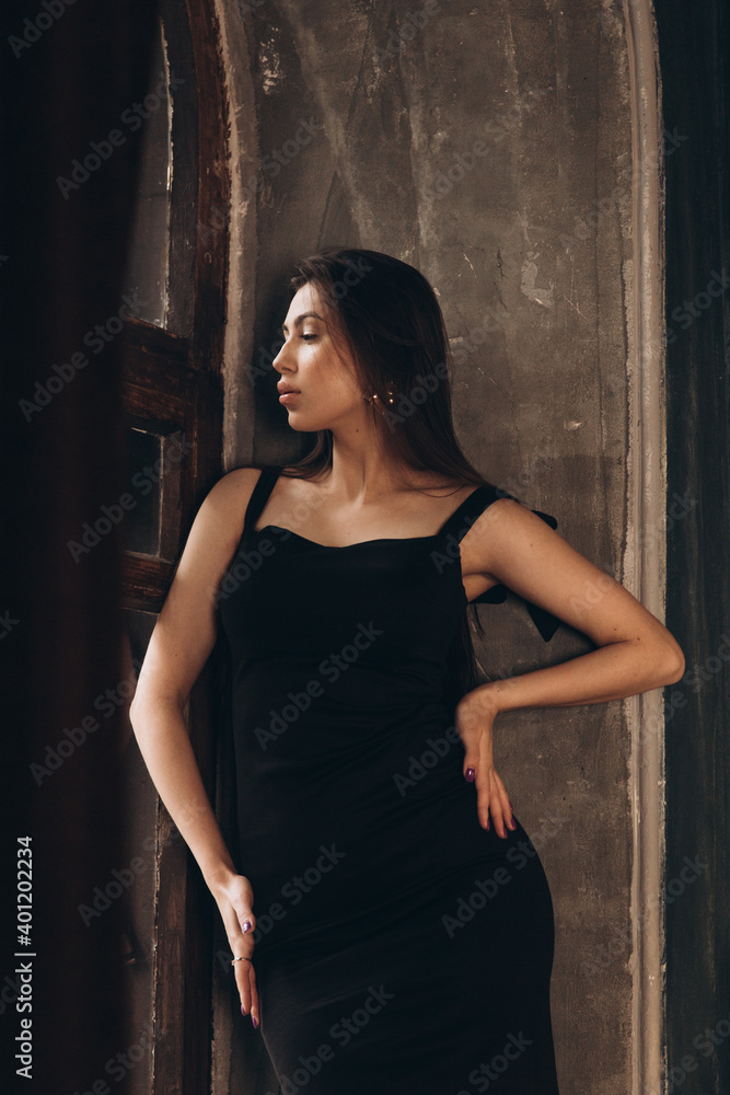Fototapeta premium Fashion photoshooting in a photo studio of a beautiful girl in a black dress