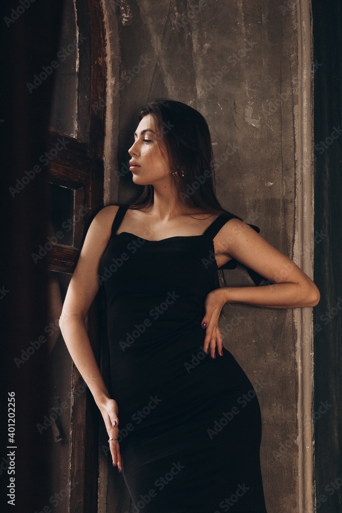 Fototapeta premium Fashion photoshooting in a photo studio of a beautiful girl in a black dress
