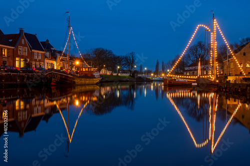 Decorated traditional boats in the harbor from Dokkum in the Netherlands at christmas at sunset