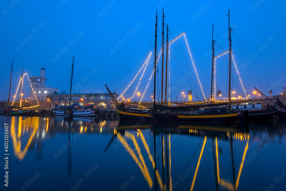 Decorated traditional sailing ships in the harbor from Harlingen in the Netherlands in christmastime at night