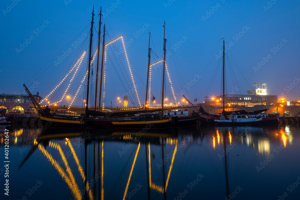 Decorated traditional sailing ship in the harbor from Harlingen in the Netherlands in christmastime at night
