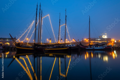 Decorated traditional sailing ship in the harbor from Harlingen in the Netherlands in christmastime at night