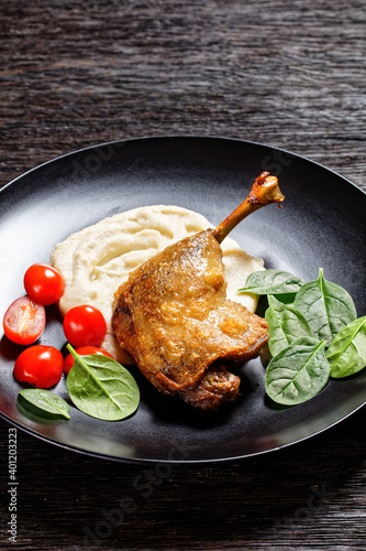 Duck confit with parsnip puree on a black plate