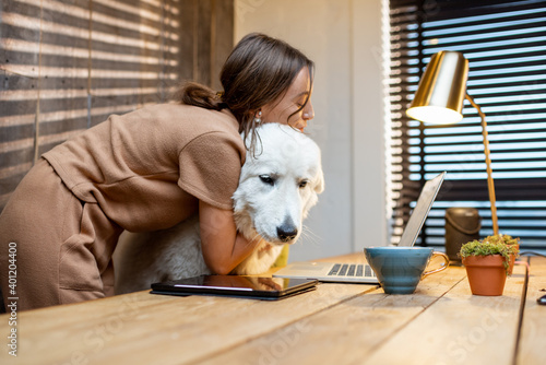 Young woman with a cute white dog working on a laptop in the home office