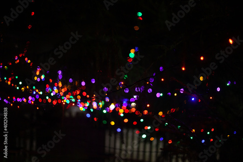 Many brightly blurred multicolored garland lights on a black background