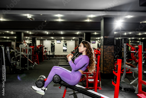 A girl in sportswear in a professional gym works out with fitness equipment. Healthy lifestyle concept