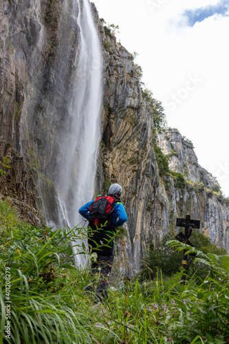 Hombre joven senderista junto a una cascada en el nacimiento del rio Asón en Cantábria