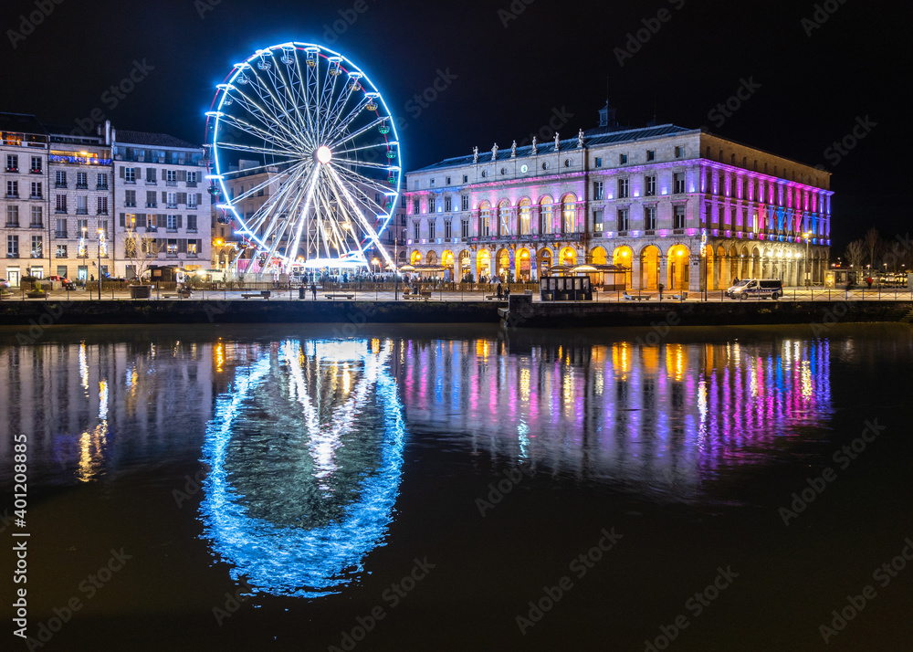 The ferris wheel and the town hall at night in Bayonne, France. Reflection on the river.