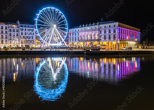 The ferris wheel and the town hall at night in Bayonne, France. Reflection on the river.