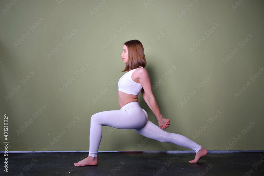 Beautiful brown-haired young woman wearing black sportswear practicing yoga, attractive girl working in modern yoga studio