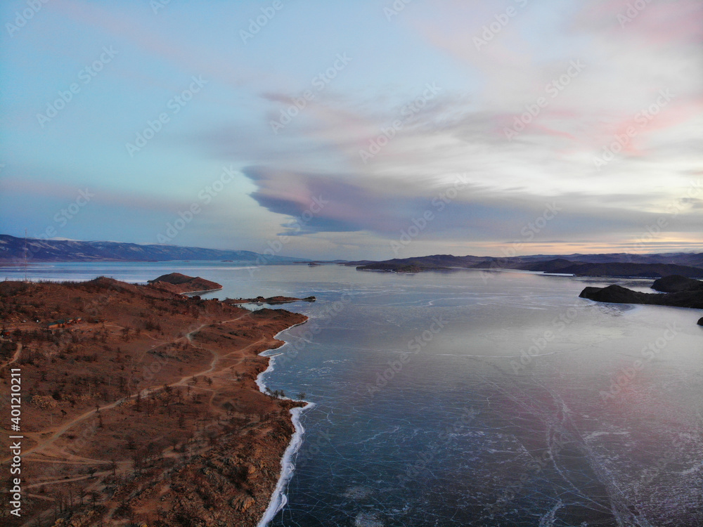 Winter morning over lake Baikal. View of the frozen lake from the air, Small Sea Strait, transparent smooth ice with cracks.