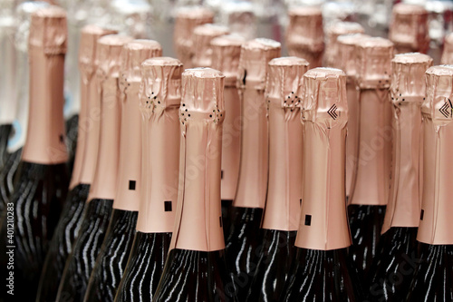 Sparkling wine bottles in golden foil for celebration. Champagne in wine store, alcohol industry