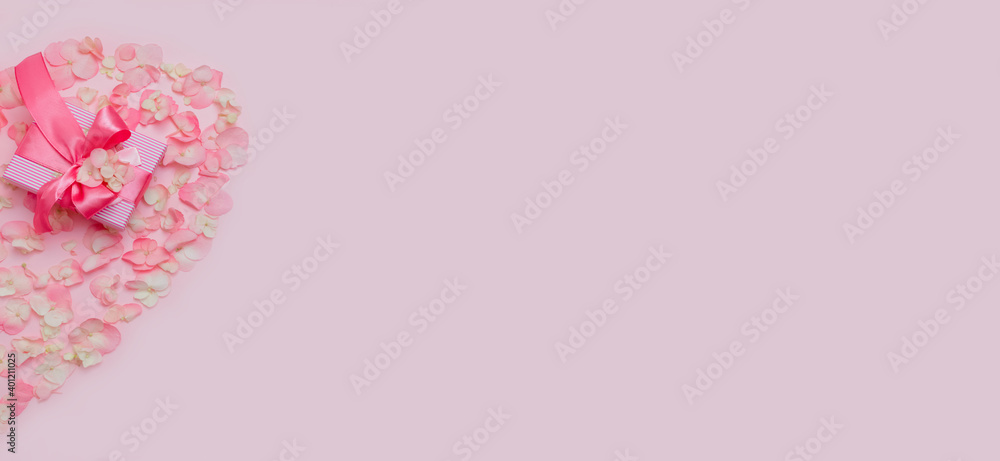 Valentine's Day.Heart of pink hydrangea petals with gift on pink background.women's day.Mother's Day,greeting card.Banner.Advertising for the store and holiday sale.copy space